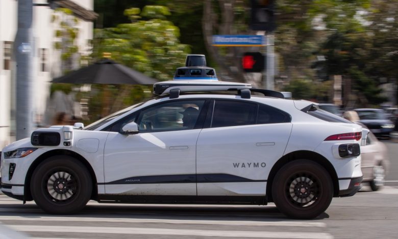 A Waymo autonomous vehicle operating on a tree-lined street in Santa Monica.