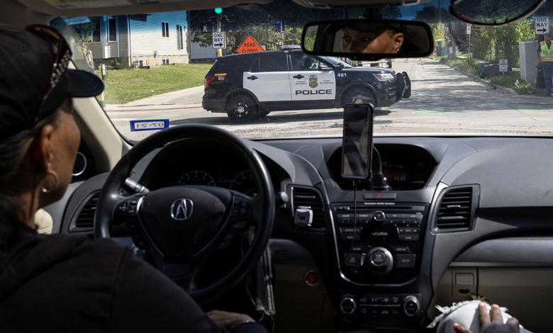 A local resident looks at a police vehicle driving along a street north of Minneapolis on Sept. 9, 2021.