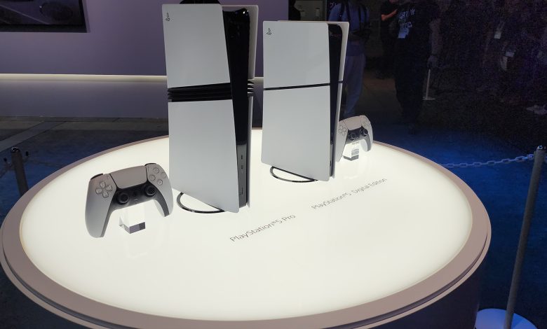 A lit table holds a PS5 Pro, and a PS5 all digital, the former standing noticeably taller.