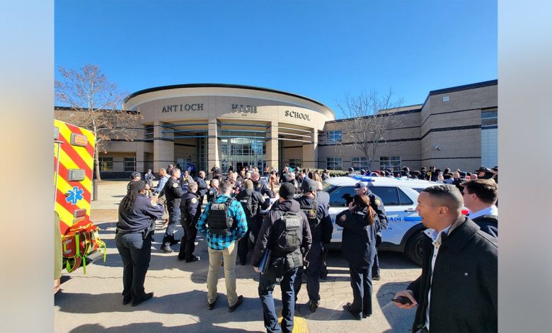 A crowd of civilians and police officers gathers outside of Antioch High School.