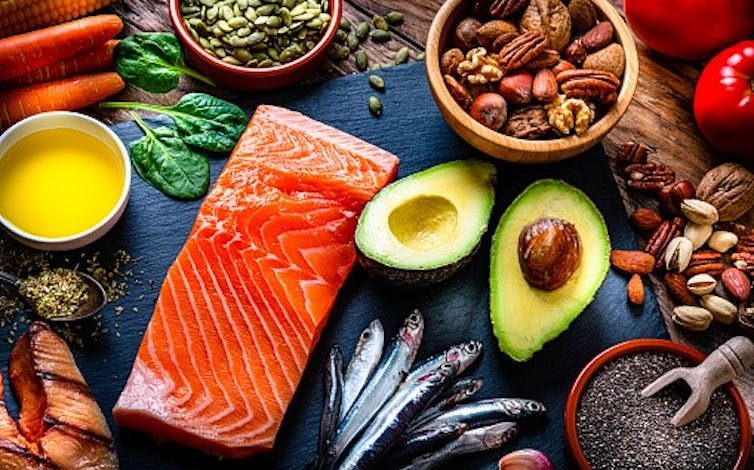 A display of foods rich in omega-3 fatty acids, including salmon, avocado and a variety of nuts and seeds.