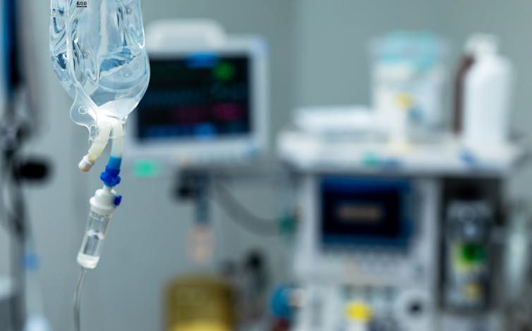 Close-up of IV bag with other medical equipment in the background out of focus