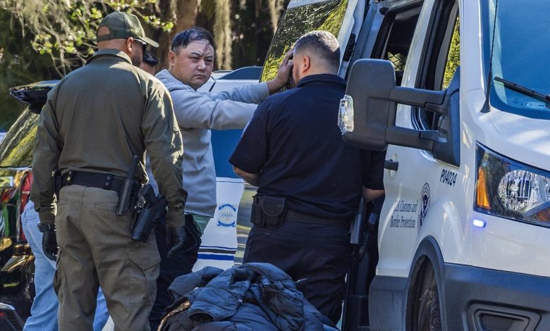 Authorities process a man who has his hands on the side of a van