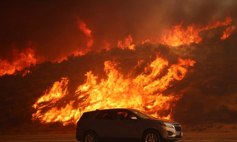 A vehicle rides past a hillside engulfed in flames caused by the Hughes Fire in Castaic, Calif., Wednesday.