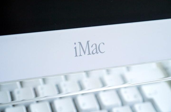 A close-up of an Apple iMac G4 showing the "iMac" logo.