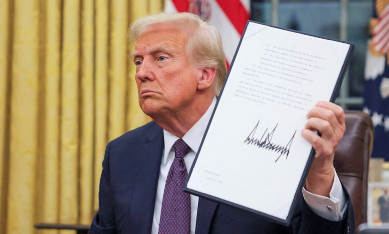 President Donald Trump holds up a signed document