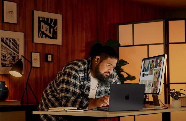 A person using a MacBook with an Apple Studio Display.