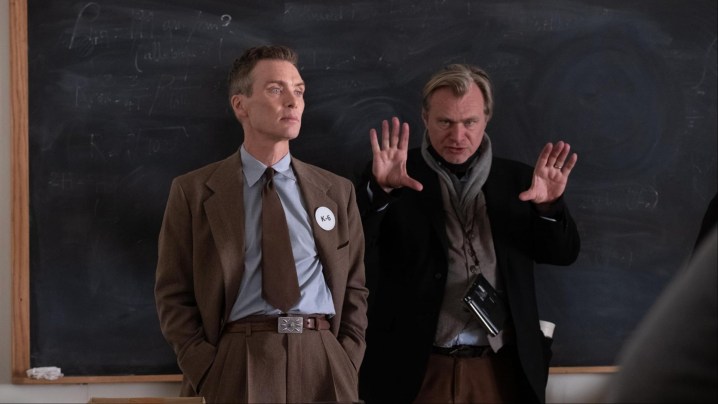 Christopher Nolan puts his hands up next to Cillian Murphy in Oppenheimer.