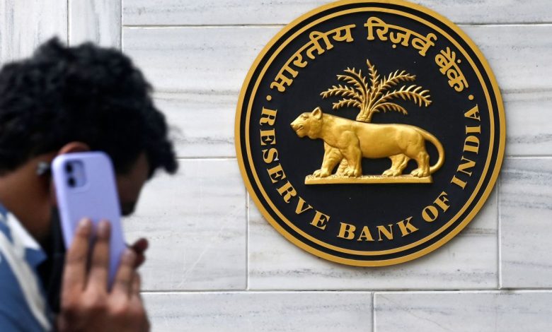 man on mobile phone walking past Reserve Bank of India sign