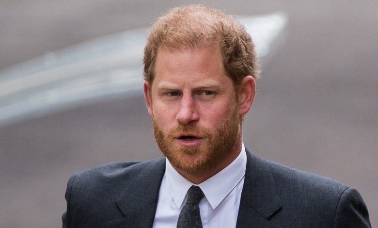 Prince Harry looks serious as he walks in a dark suit and tie