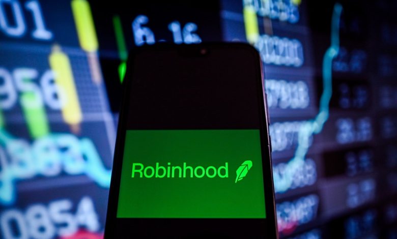 This photo illustration shows a Robinhood logo is displayed on a smartphone with stock market percentages on the background.