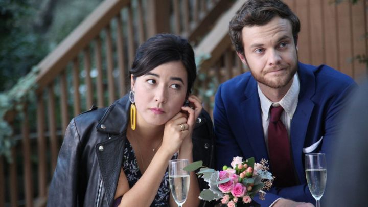 A woman leans into a guy at a table.