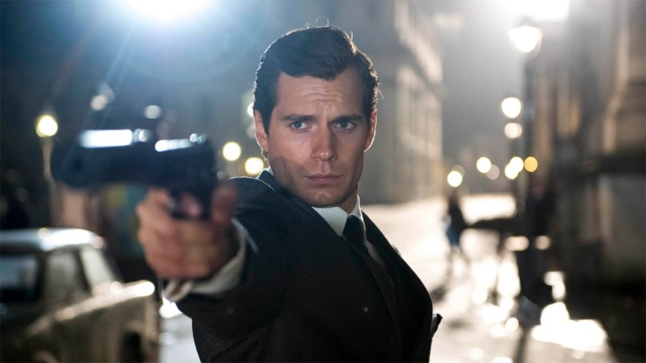 Henry Cavill as Napoleon SOlo aiming a gun at someone off-camera in The Man From U.N.C.L.E.