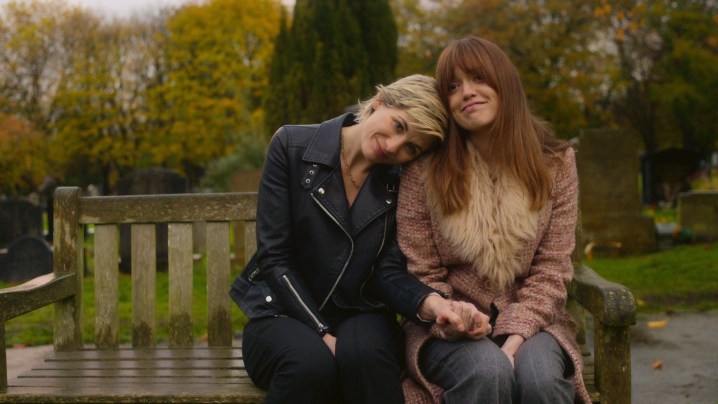 A woman leans up against another woman on a bench in Toxic Town.