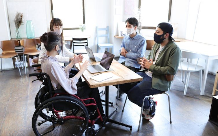 Woman on wheelchair with her colleague at office