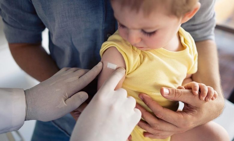 Doctor putting a patch on little boy's shoulder after vaccination.