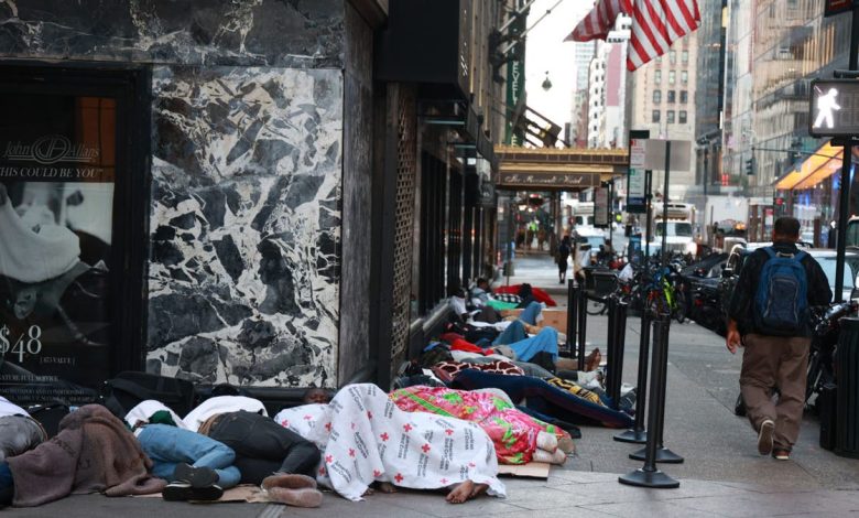 Migrants sleep on the street outside the Roosevelt Hotel