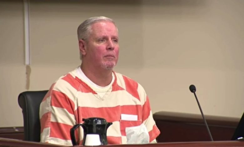 Colin Gray wearing an orange-and-white jumpsuit in court