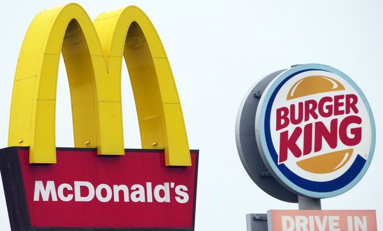 The logos of McDonald's as well as Burger King stand next to the respective fast food restaurants at a highway rest stop.