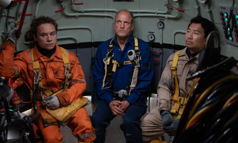 Finn Cole, Woody Harrelson, and Simu Liu sit, looking worried, in a diving bell in a still from the movie Last Breath.