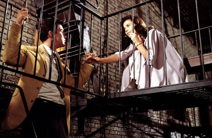 A man and woman look at each other on a fire escape.