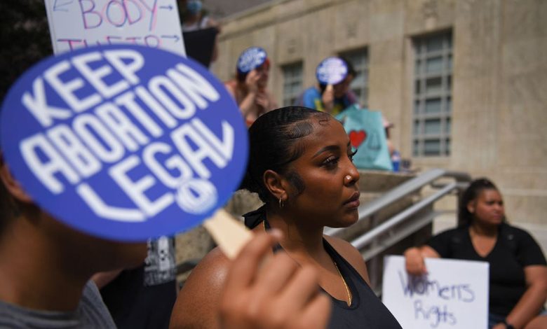 Pro-choice advocates stand outside with signs, one sign saying "Keep Abortion Legal"