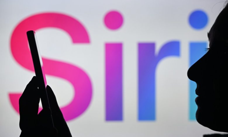 An image of a woman holding a cell phone in front of the Siri logo displayed on a computer screen.