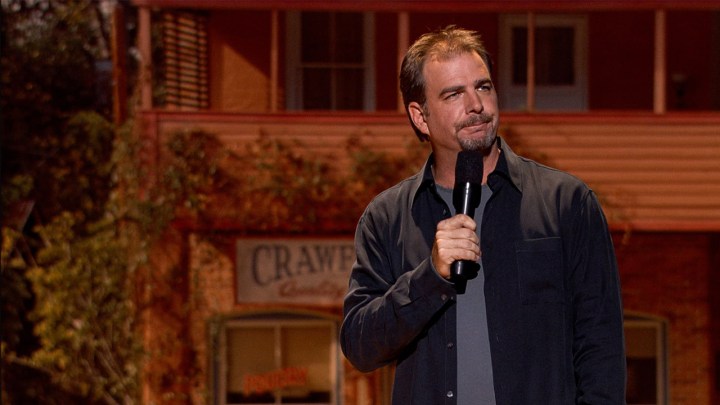 A comedian standing in stage holding a mic in Blue Collar Comedy Tour: The Movie.