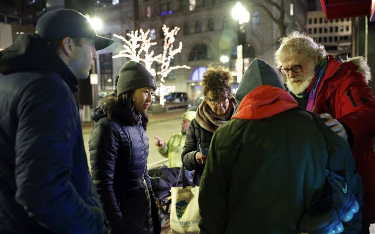 People in winter coats stand in a circle during an annual count of people experiencing homelessness in Boston.