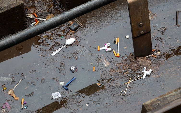 Used needly, Narcan dispensers and other items collects in large puddle on ground