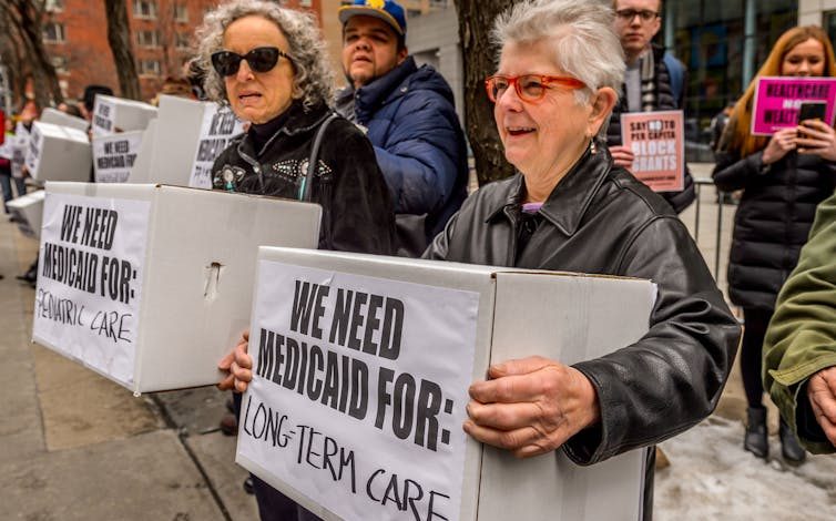 Women carry boxes labeled 'We need Medicaid for Long Term Care' and We need Medicaid for Pediatric Care' at a protest in 2017.