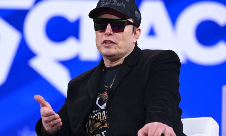 Elon Musk on stage at CPAC in Maryland with sunglasses on and a MAGA hat