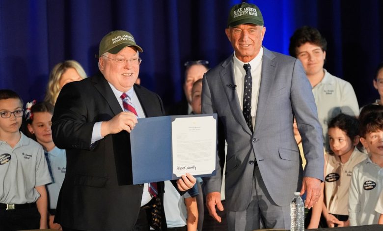 West Virginia Gov. Patrick Morrisey stands next to Health and Human Services Secretary Robert F. Kennedy Jr. as they wear Make America Healthy Again hats.