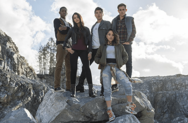 A group of teens stand on rocks.