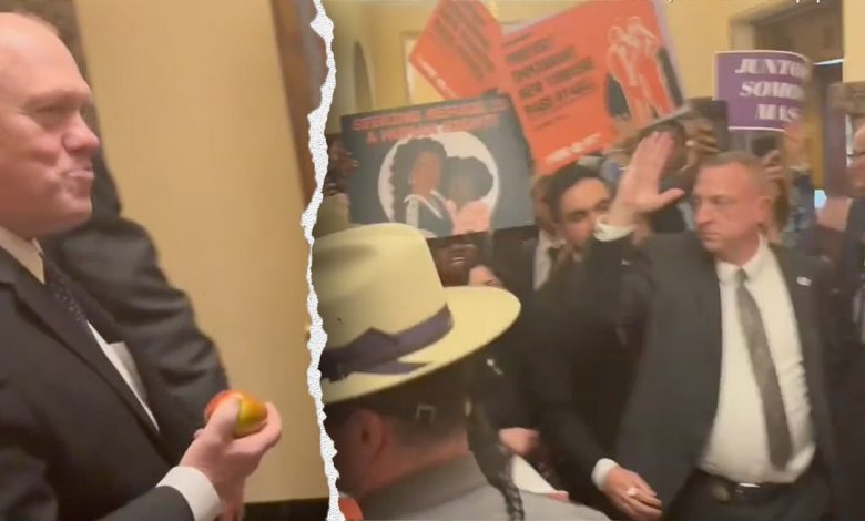 Tom Homan eats an apple in front of protesters on Wednesday.