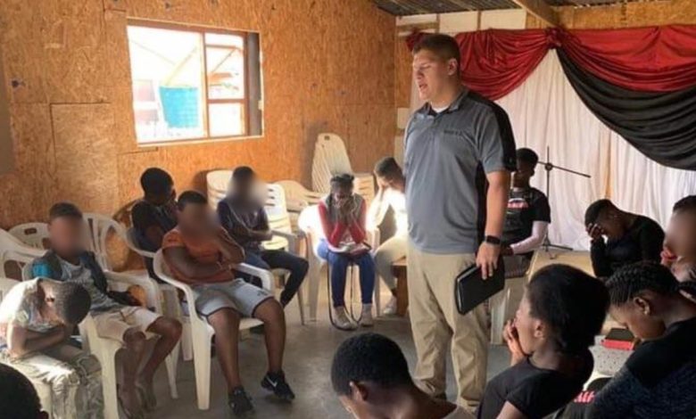 Josh Sullivan prays with a group of South African children
