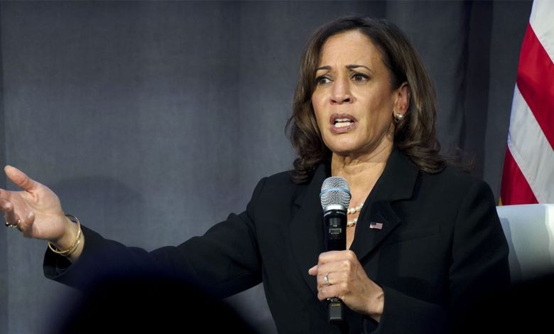 Kamala Harris dressed in all black holds mic during event