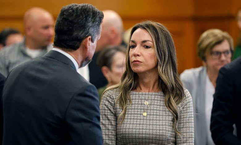 Karen Read, wearing a brown plaid dress, talks with her attorney Alan Jackson, who has his back turned and is wearing a dark suit