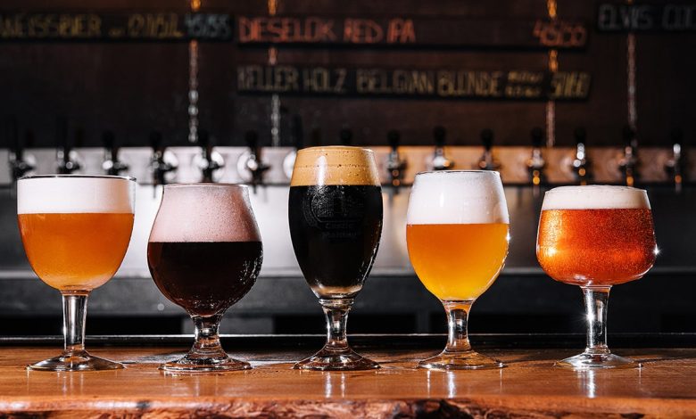 Beer glasses of many varieties with different colors and types of beer, all lined up along a bar