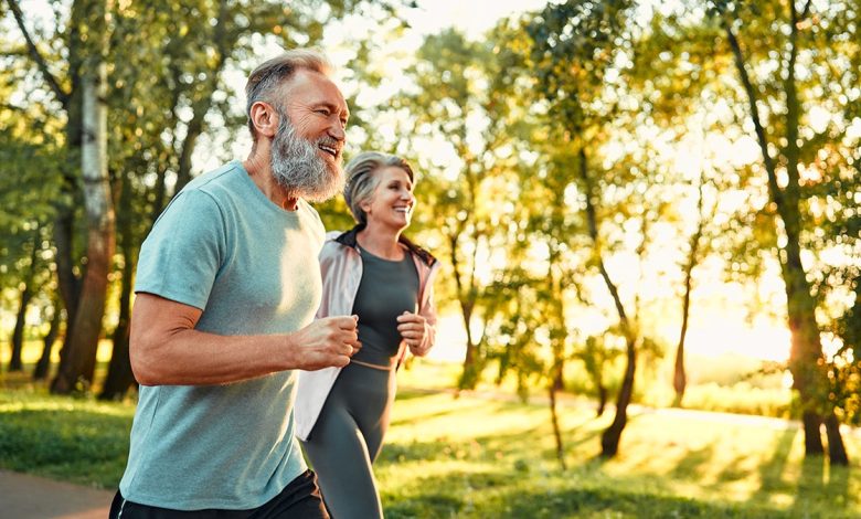 Elderly couple running next to each other outdoors.