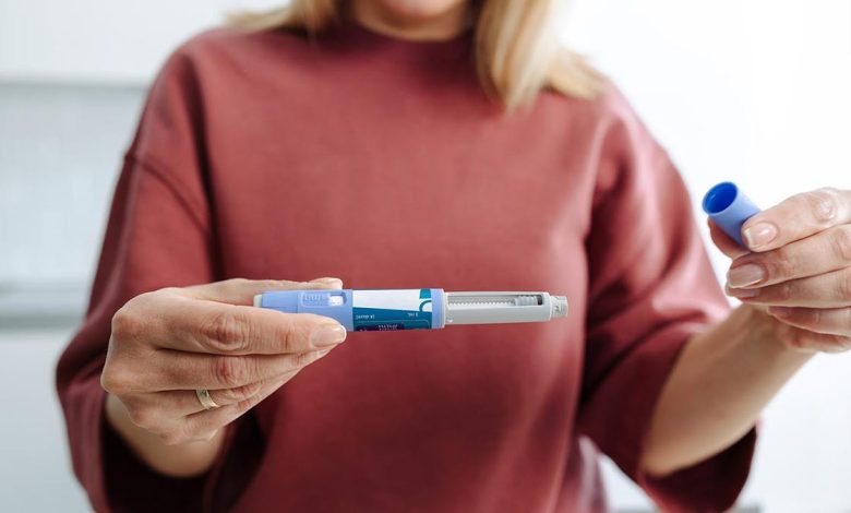 A person holding and preparing a medical injection pen, demonstrating its usage during a healthcare routine.