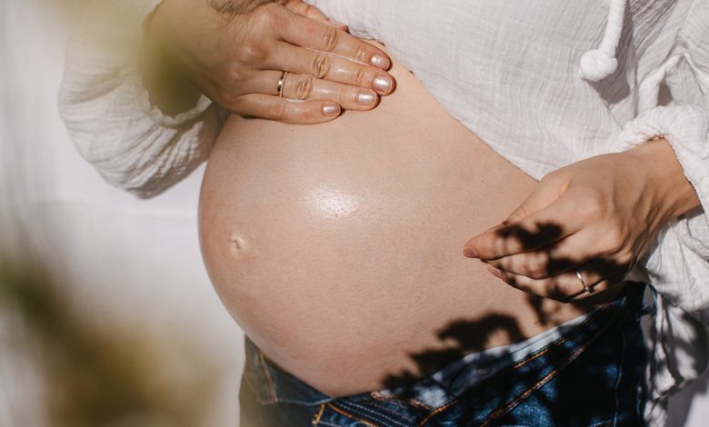 a pregnant woman rubs her belly with oil