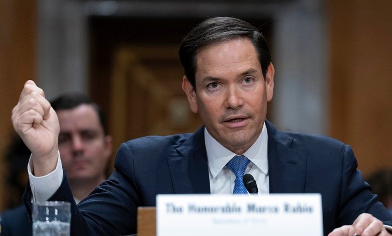 Secretary of State Marco Rubio testifying in a dark suit and blue tie