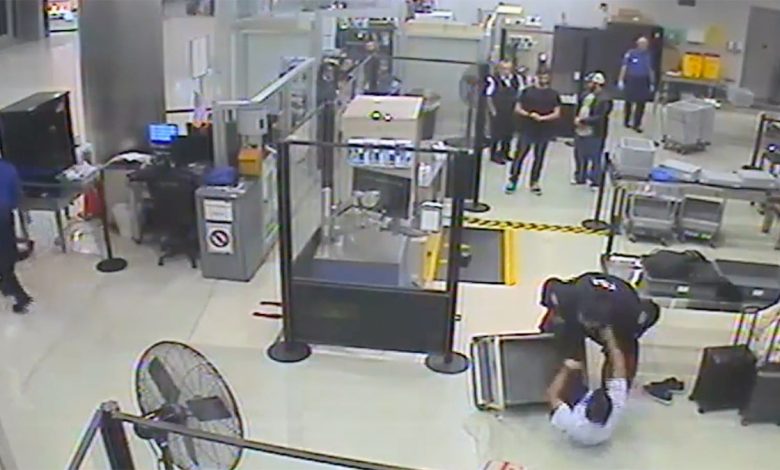 Video still of TSA officers pinning Cameron McDougall to the floor near a security checkpoint at Miami International Airport