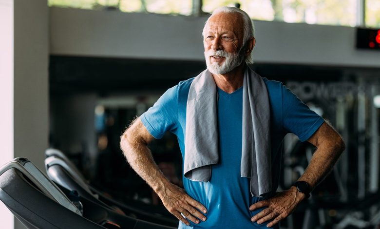 Older man standing on treadmill in gym, looking confident and fit with a towel around his neck: used in piece about vitamin d being able to protect telomeres and support longer living