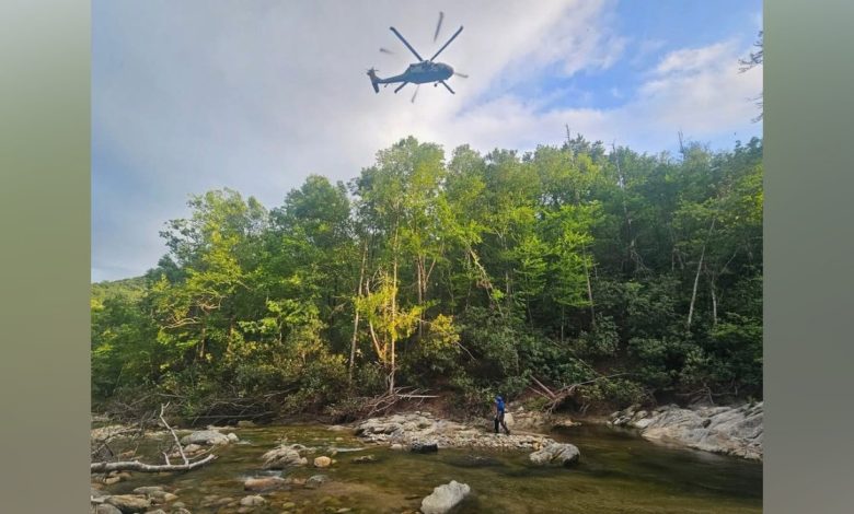 A Black Hawk helicopter flies over a wooded area in Avery County, NC, to rescue a snake bite victim