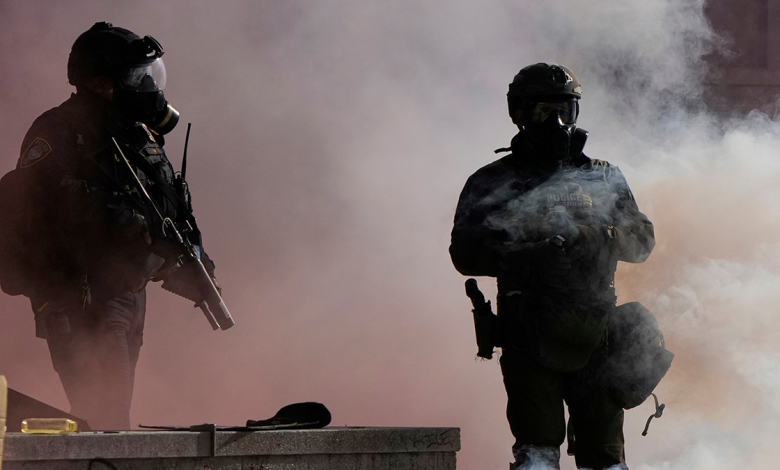 Law enforcement agents stand after tear gas was deployed outside the U.S. Immigration and Customs building during a protest Saturday, June 14, 2025, in Portland, Ore.