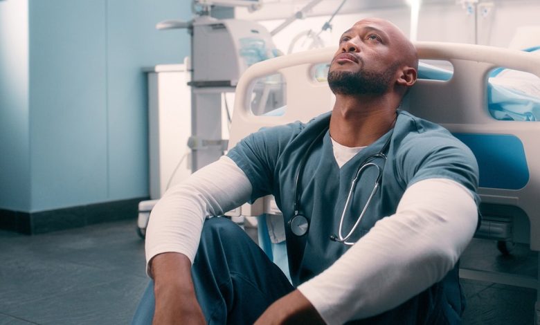 tired healthcare worker sits on floor of hospital