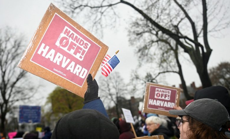 A protester holds up a sign that reads "Hands off! Harvard"