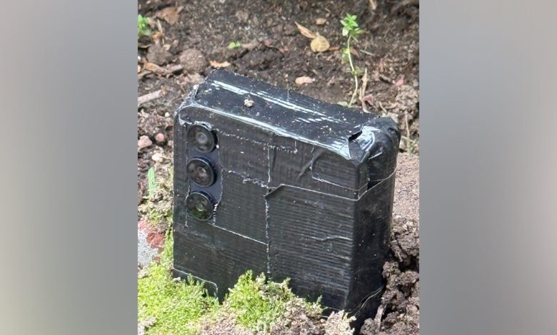 Hidden phone buried beneath dirt in Queens, New York, yard with cameras sticking out.
